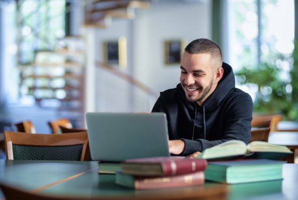 Studente che usa un computer e dei libri nella biblioteca della SSML Pisa